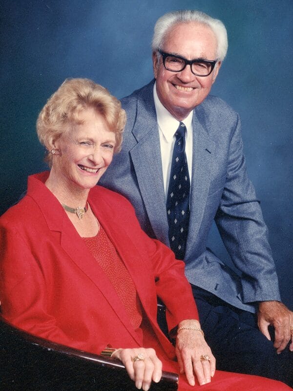 A man and a woman smiling and posing together for a photo in a casual outdoor setting.
