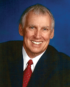 A man in a suit and tie smiling confidently at the camera.