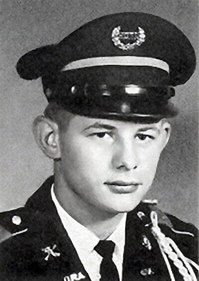 A young man in a uniform smiles while posing for a photo, showcasing pride and confidence in his appearance.