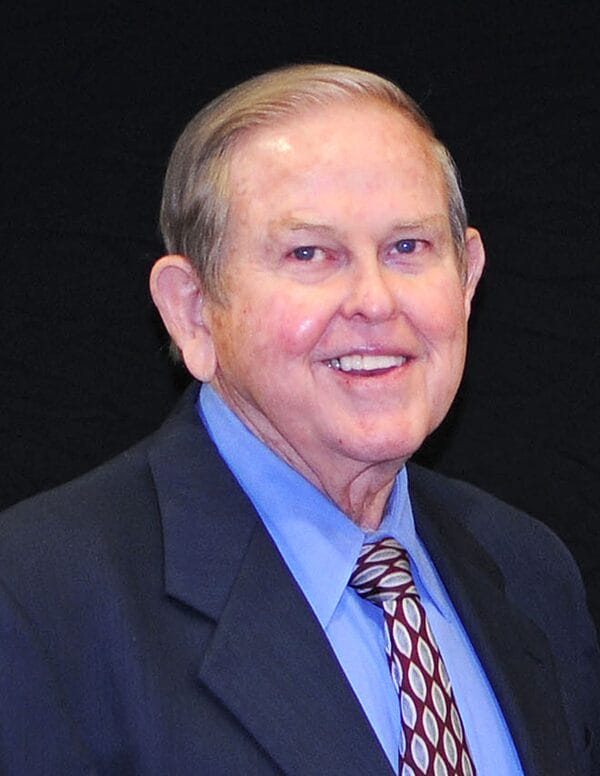Older white male smiling in a professional headshot. He is wearing a suit and tie.