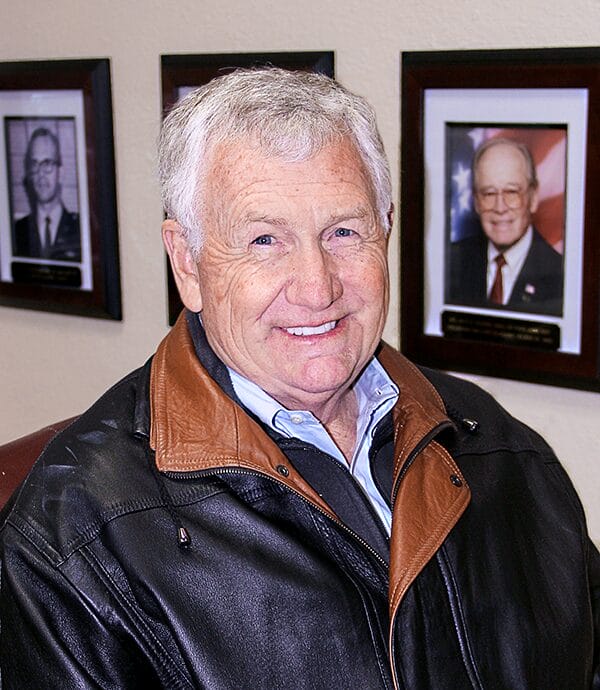  A man stands confidently wearing a black leather jacket, showcasing a casual yet stylish look.