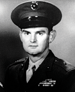  Black and white photo of a man in military uniform, standing confidently with a serious expression.
