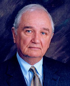 White male with white hair. He is wearing a tie and a suit jacket.