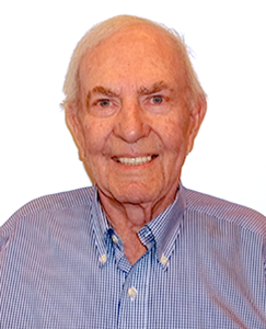 An older man wearing a blue and white shirt, smiling and looking directly at the camera.