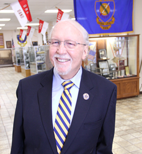 A man in a suit and tie stands confidently in a well-lit room, exuding professionalism and poise.