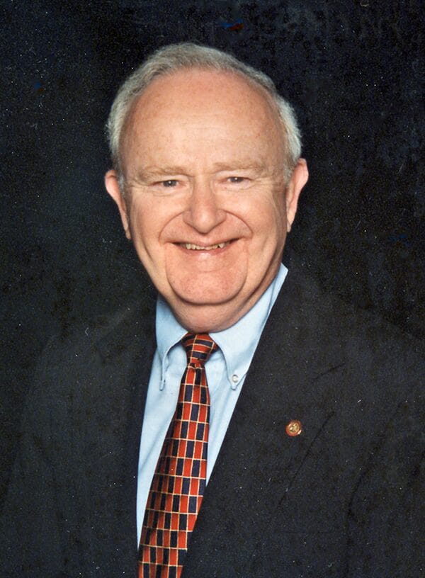 A man in a suit and tie smiles confidently, showcasing a professional appearance.