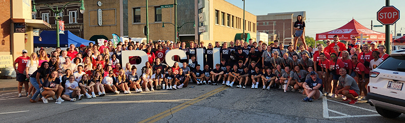 RSU students wearing RSU pride clothing pose in street with RSU letters.