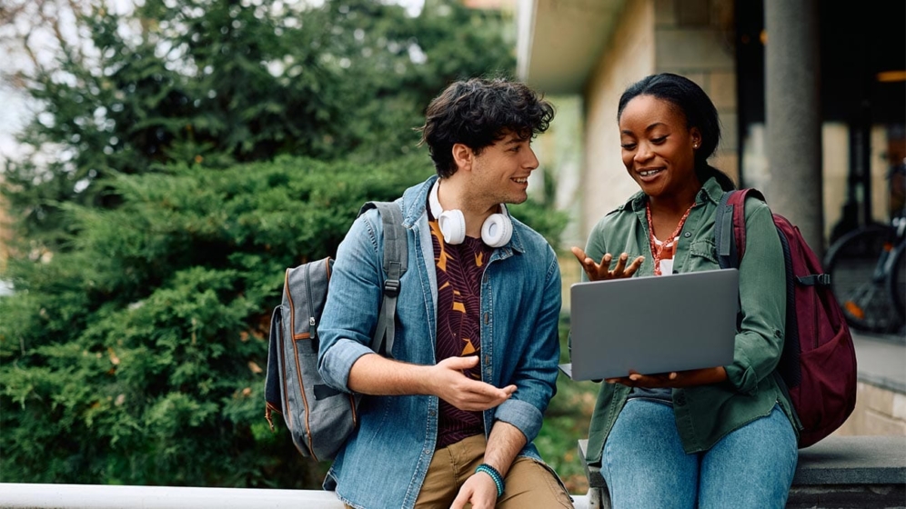 Student and her friend browsing on laptop on campus.