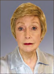 Older woman with short blonde hair and red lipstick, wearing a light blue satin blouse, posed against a solid gray background.