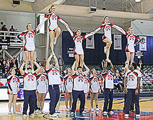 Cheerleaders in a pyramid at a basketball game.