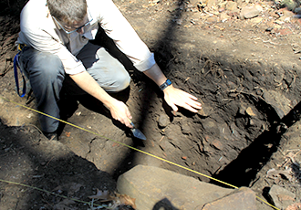 Man down in hole and diggin in dirt.