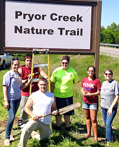 Students posing under the Pryor Creen Nature Trail sign.