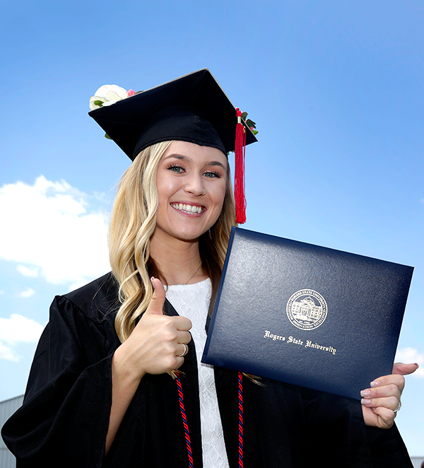 Girl in cap and gown holding diploma giving a thumbs up!