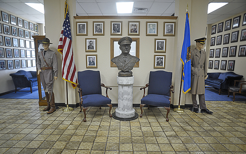 bust statue on pedestal with pictures hanging on wall