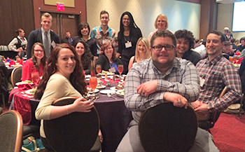 Communications students posing around a banquet table.