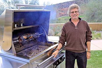 Steven Raichlen standing next to barbeque grill.