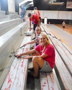 RSU students scraping paint off of bleachers for comunity servce.