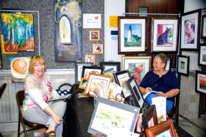 Artist sitting in their booth displaying artwork.