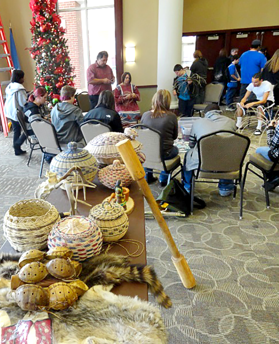 Table of Native American Baskets and attendees working on art projects in background.