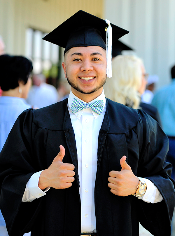 Student in cap and gown giving the thumbs up signal.