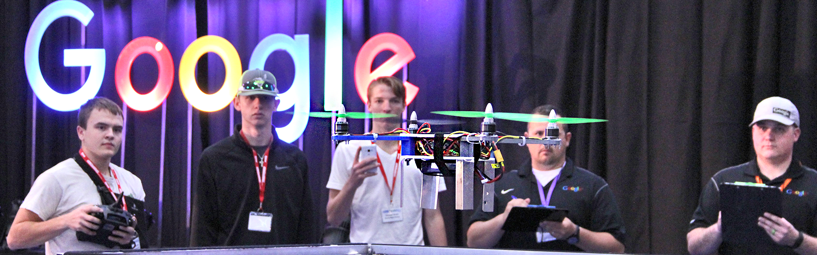 Boy flying drone with team and judges watching