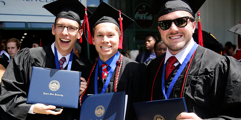 Boys in cap and gown holding diplomas