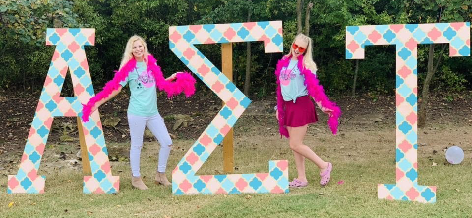 girls posing behind greek letters