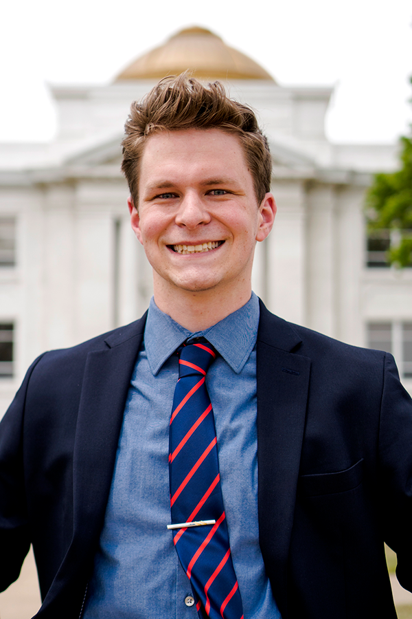 Jake Brillhart in suit standing in front of Prep Hall