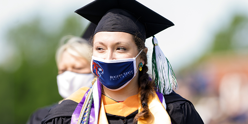 Girl in cap and gown with a Hillcat Mask on face.