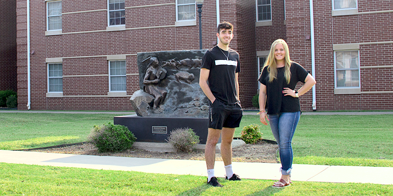 Boy and girl standing in front of statue