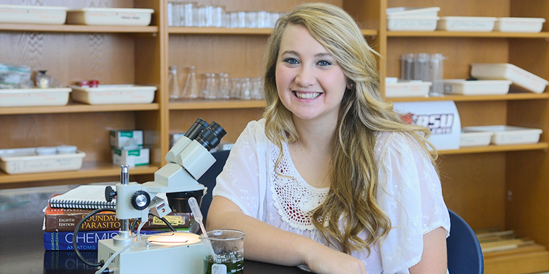 Girl in lab next to microscope