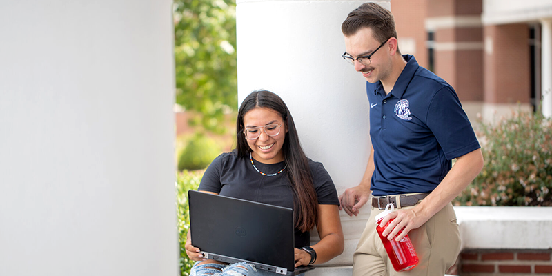 Professor and Student looking at Laptop Outside