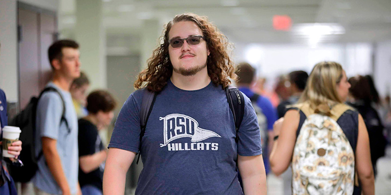 boy with long hair and sunglasses walking in hall