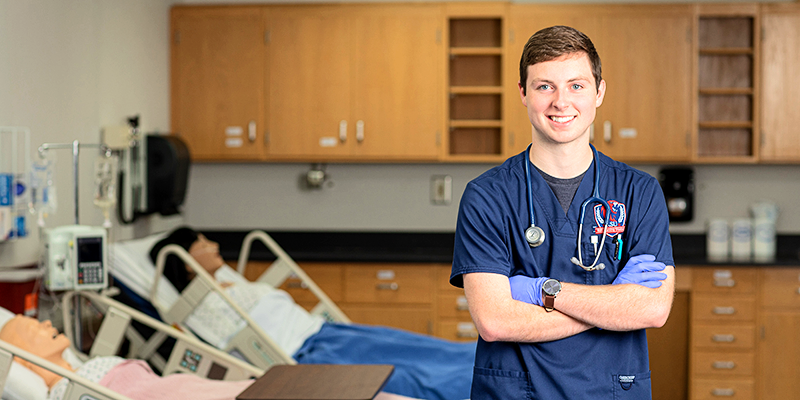 boy wearing scrubs in nursing lab