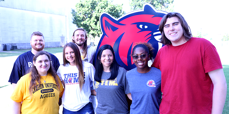 students standing by large cat head cutout