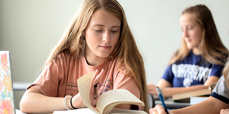 girl looking at book in class