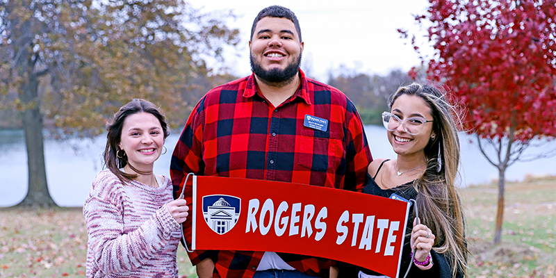 Students outside holding Rogers State flag