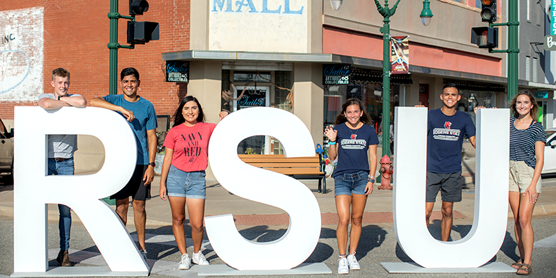 students standing by giant RSU letters