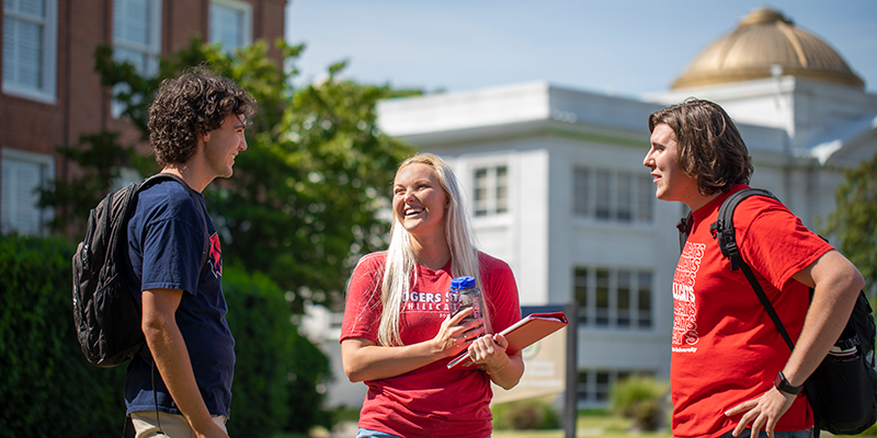 students talking in front of building with gold dome