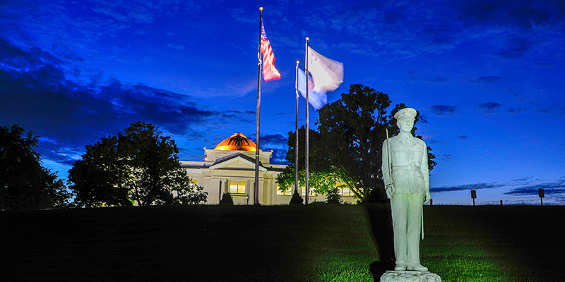 night sky with white building and flags and soldier statue