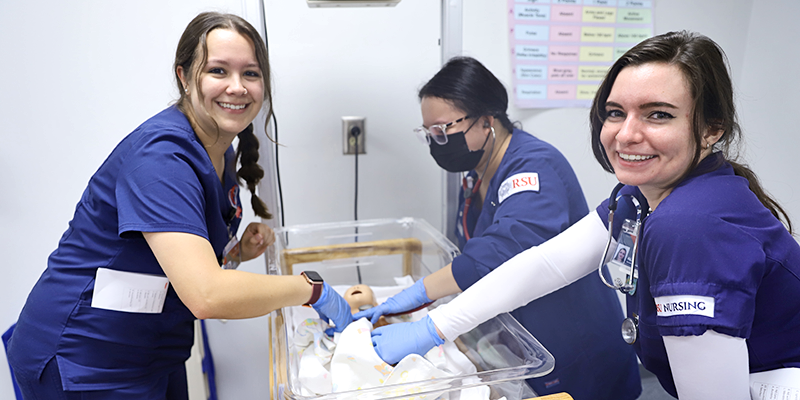 nursing students in scrubs with baby manequin