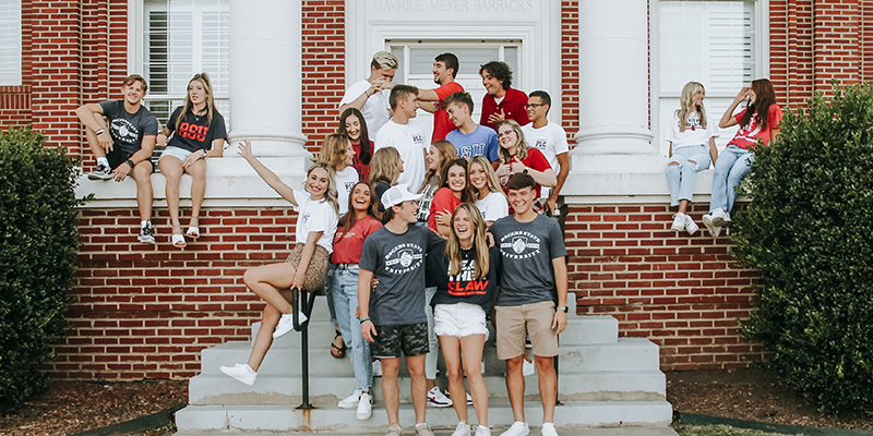 students posing on steps outside building