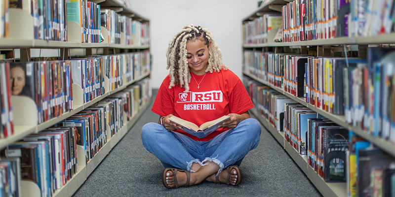 Girl reading book in floor at library