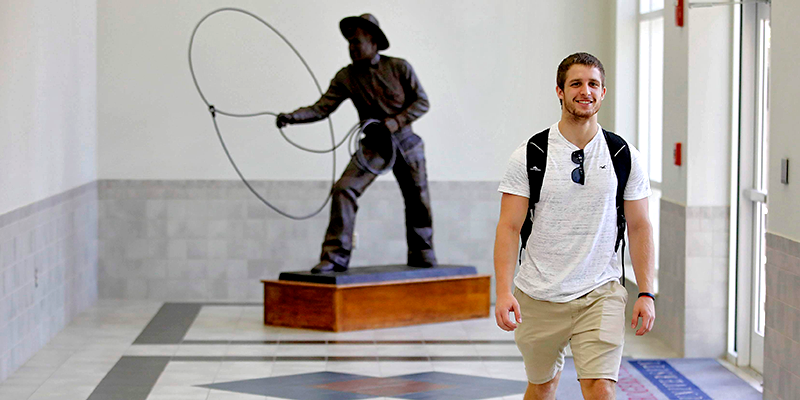 boy walking in hallway with Will Rogers Statue in background