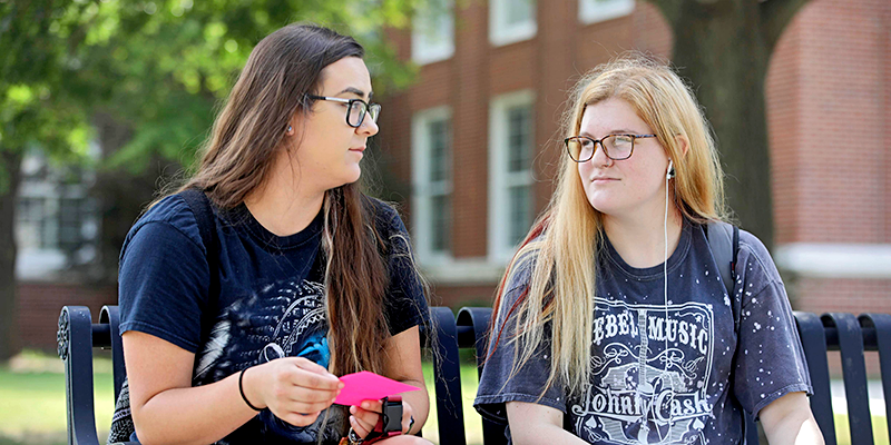 two girls talking on bench outside