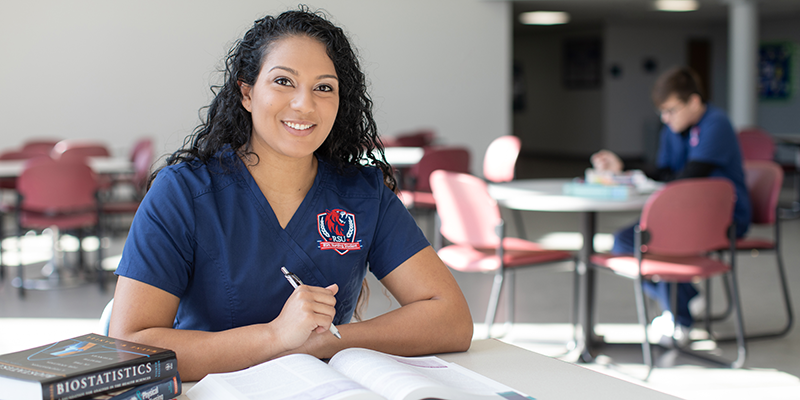 girl in scrubs studying textbook