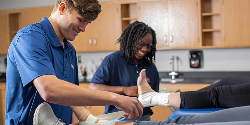 Student trainers learning to tape an ankle