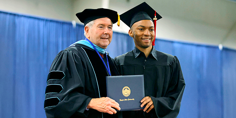 men in cap and gown holding diploma