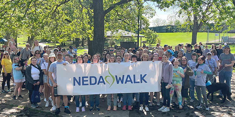 large group of people behind a NEDA WALK banner