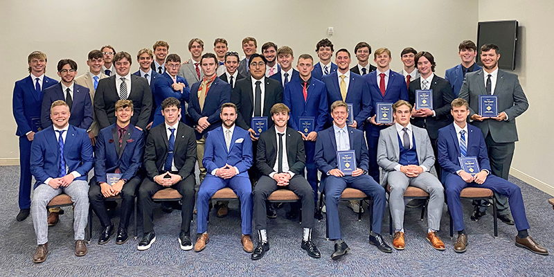 group of young men in suits holding awards